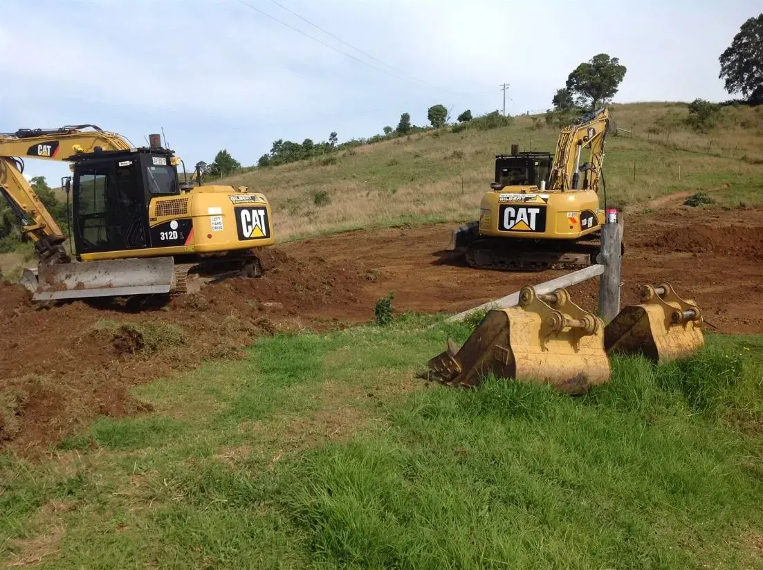 Two Orange Cat Excavators Are Working on a Dirt Field — S M & A J Gilbert Earthmoving in Mitchells Island, NSW
