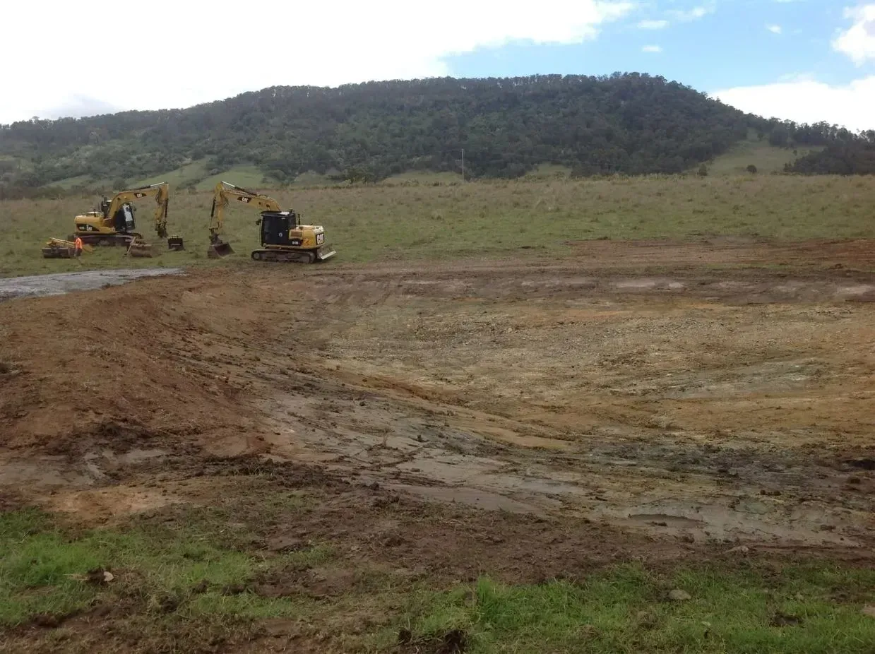 A Group of Construction Vehicles Are Working in a Muddy Field — S M & A J Gilbert Earthmoving in Mitchells Island, NSW