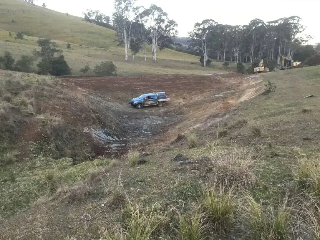 A Blue Truck is Driving Down a Dirt Road in a Field — S M & A J Gilbert Earthmoving in Mitchells Island, NSW