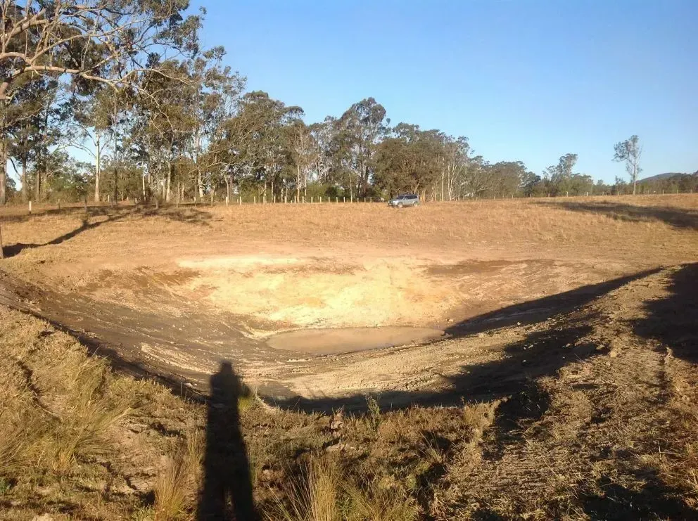 A Small Pond in the Middle of a Field With Shadow Of A Man in the Background — S M & A J Gilbert Earthmoving in Mitchells Island, NSW