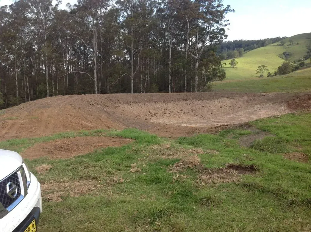 A White Car is Parked in a Grassy Field With Forest in the Background — S M & A J Gilbert Earthmoving in Mitchells Island, NSW