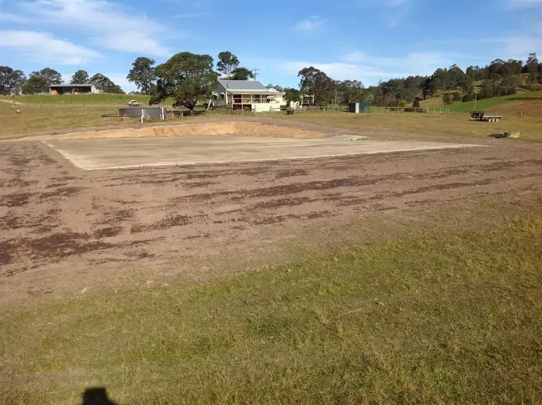 A Large Grassy Ranch Field With a House in the Background — S M & A J Gilbert Earthmoving in Mitchells Island, NSW
