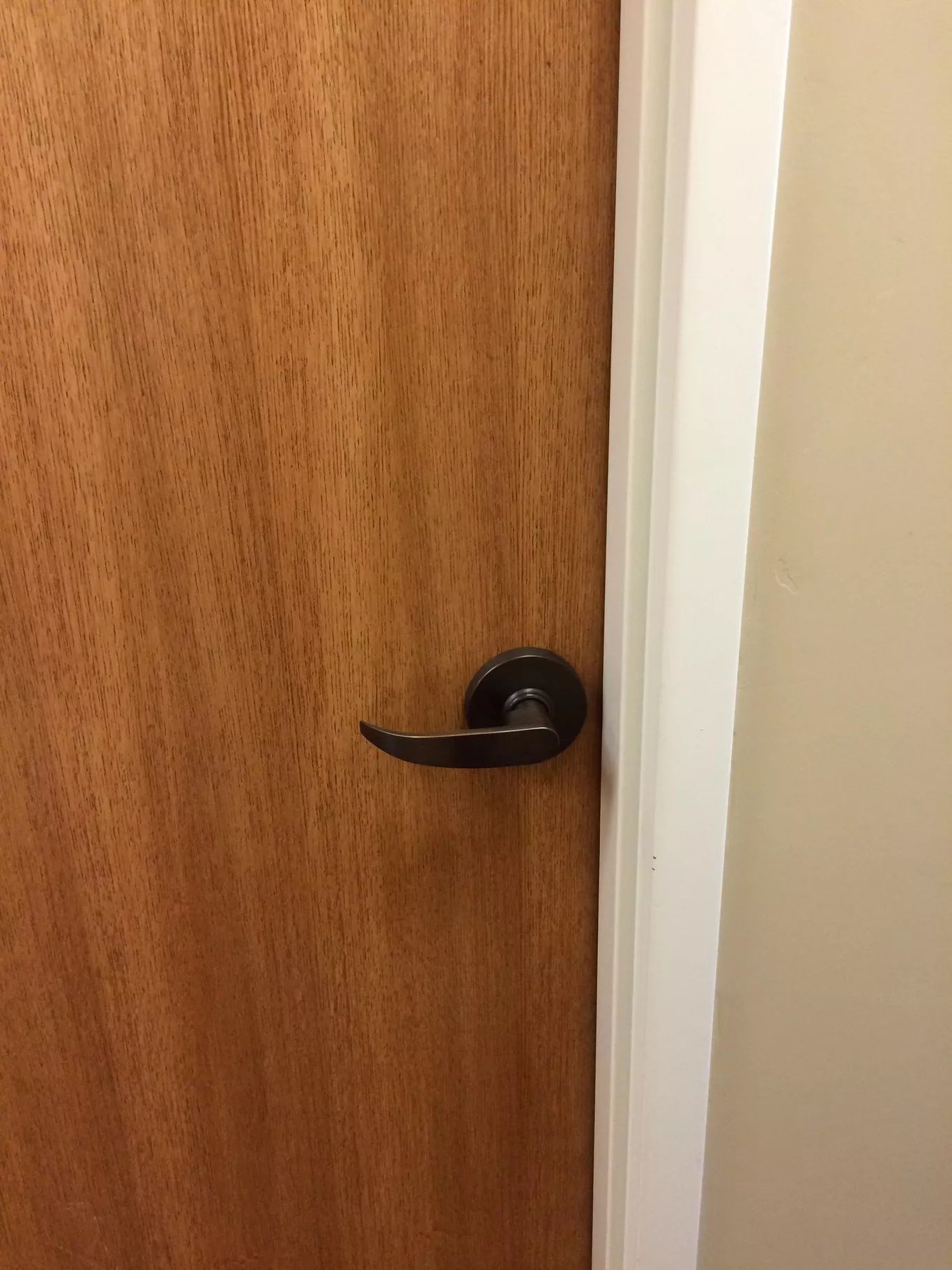 A close up of a wooden door with a black door handle.