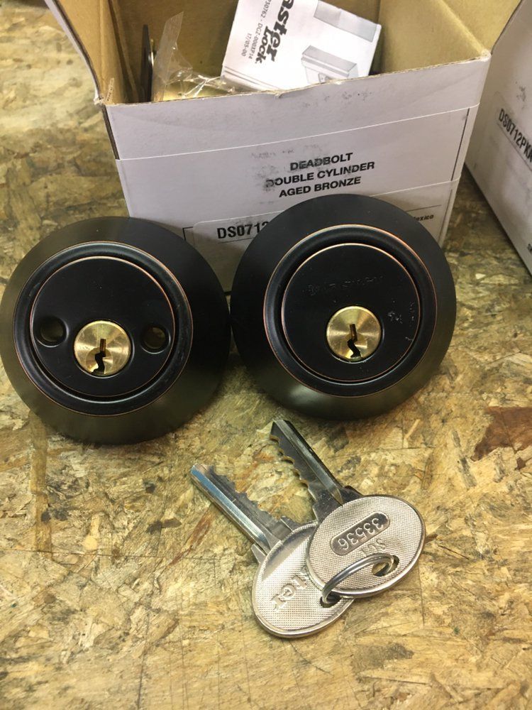 Two locks and two keys are sitting on a wooden table next to a box.