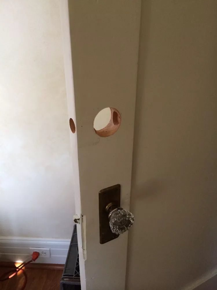 A close up of a door with a hole in it and a door knob.