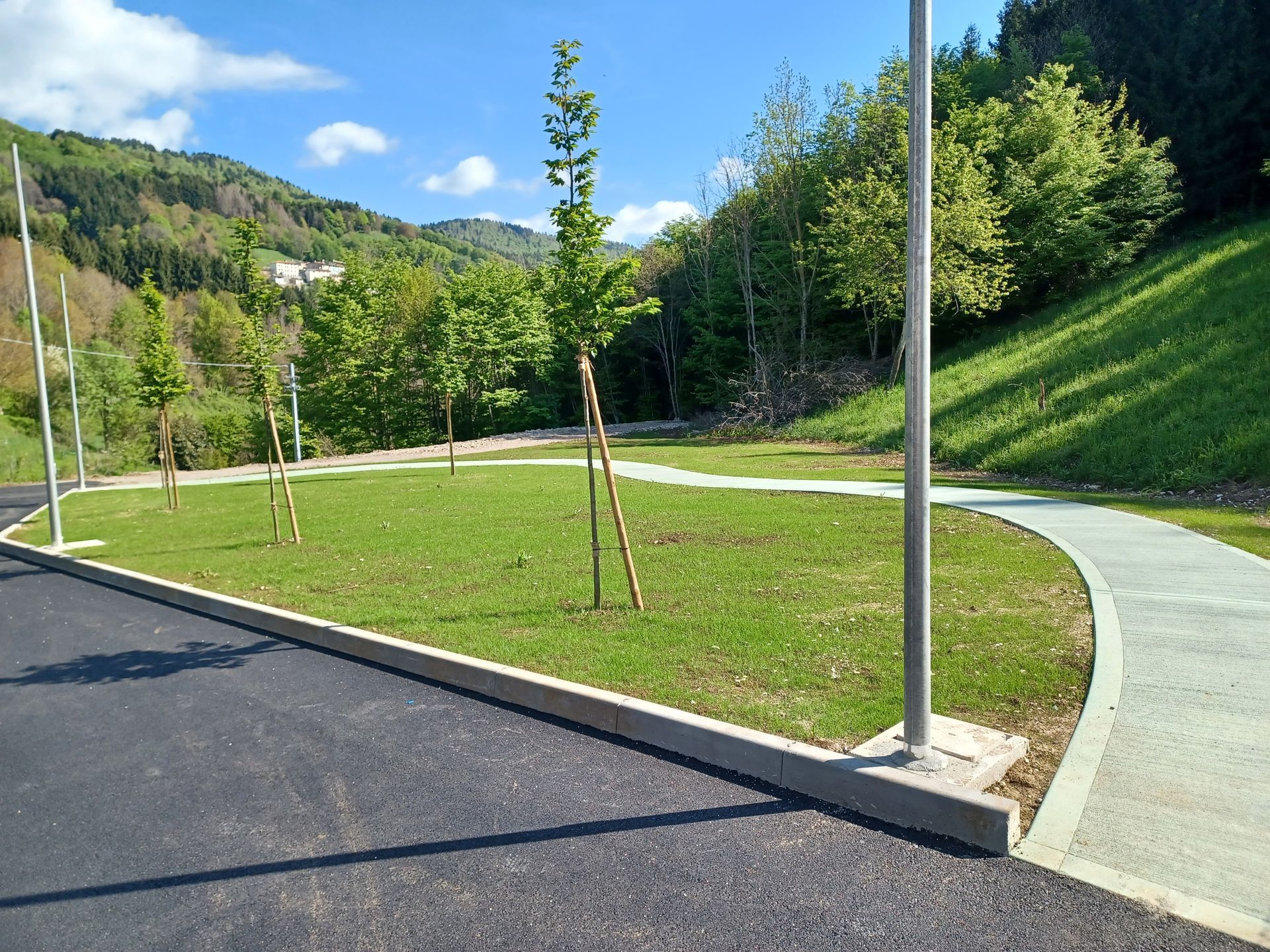 Quattro persone in abiti da lavoro sono in piedi accanto a due trattori vicino a un cartello di lavori stradali. Sullo sfondo la foresta.