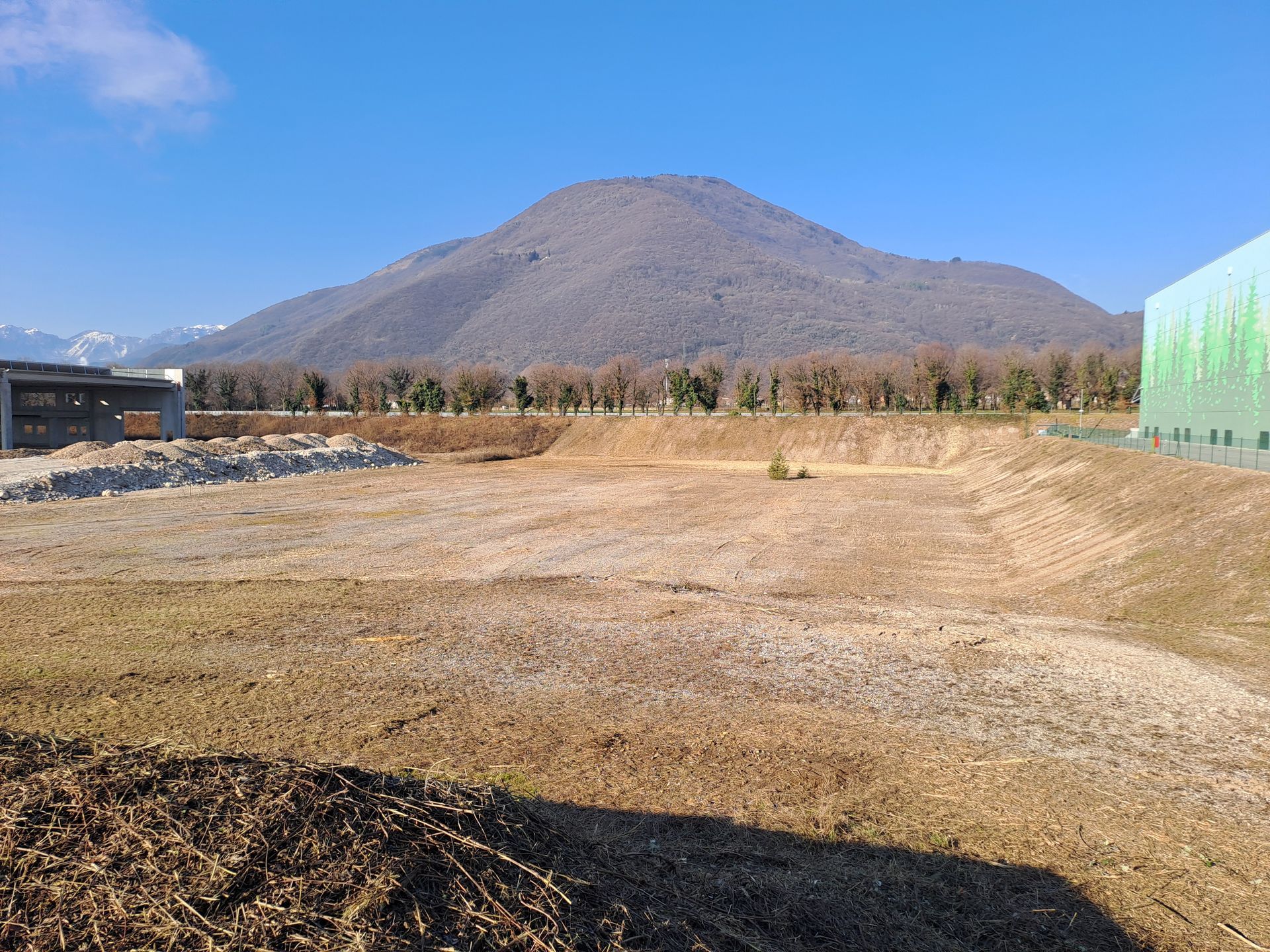 Campo sgombro con montagne ed edifici sullo sfondo. Giornata di sole.