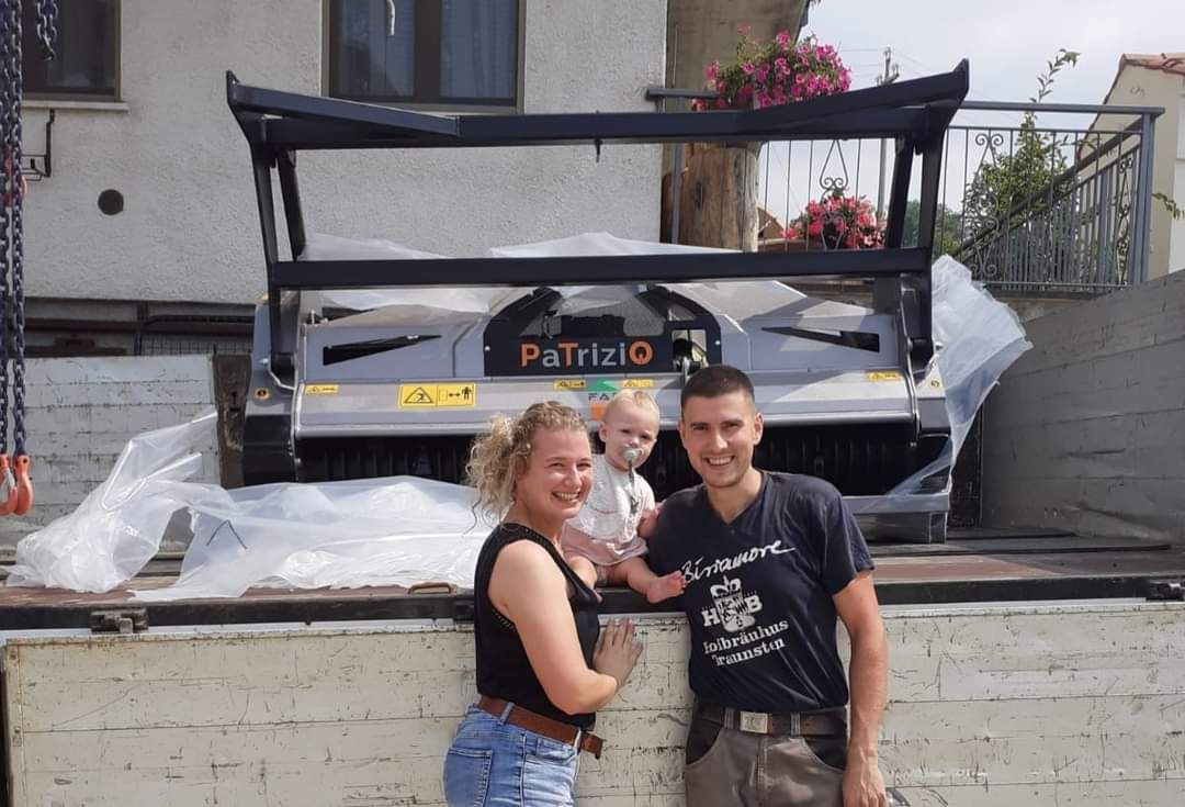 Una famiglia è in piedi con un nuovo macchinario industriale sul cassone di un camion.