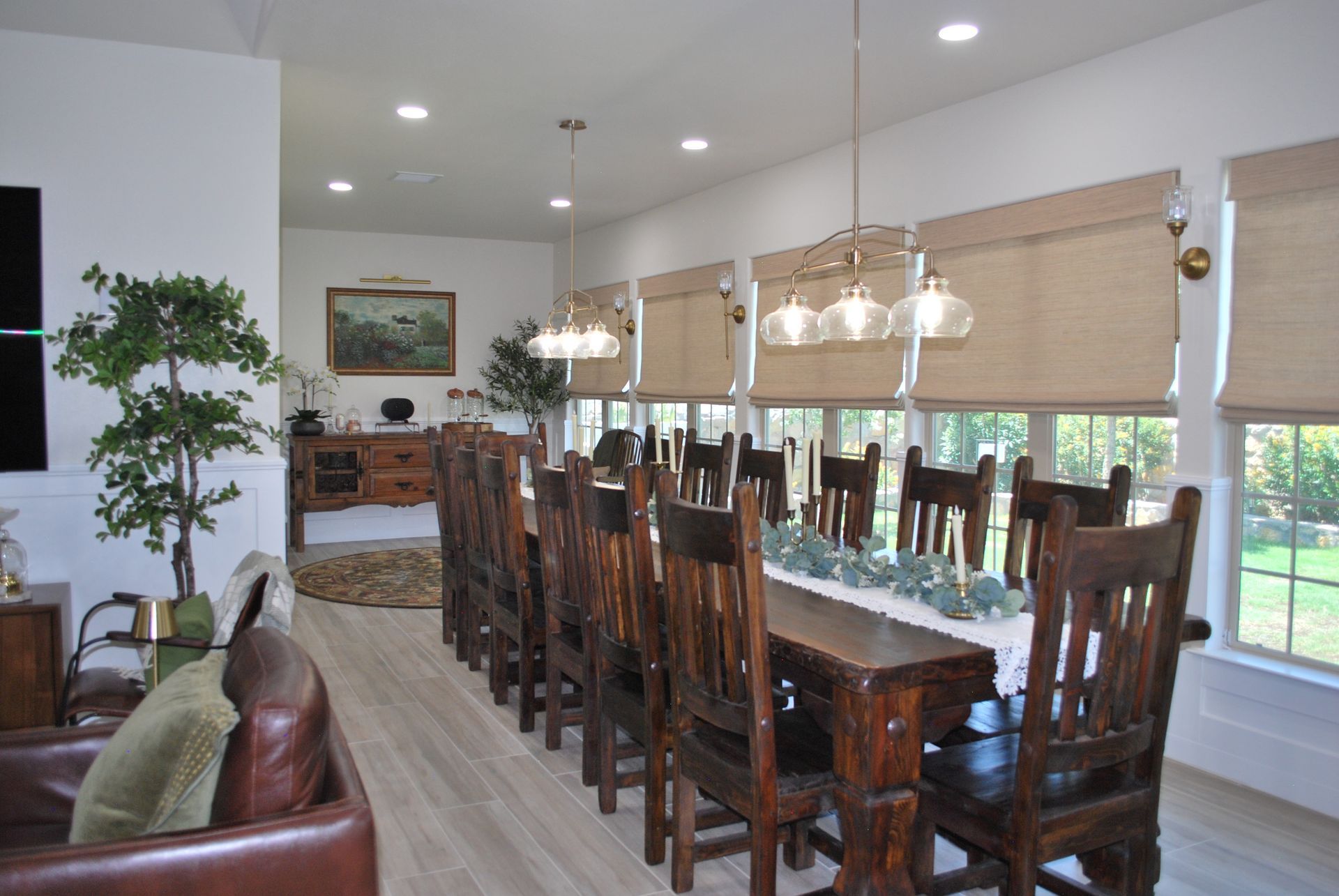 Long dining table with wooden chairs, white walls, and large windows.