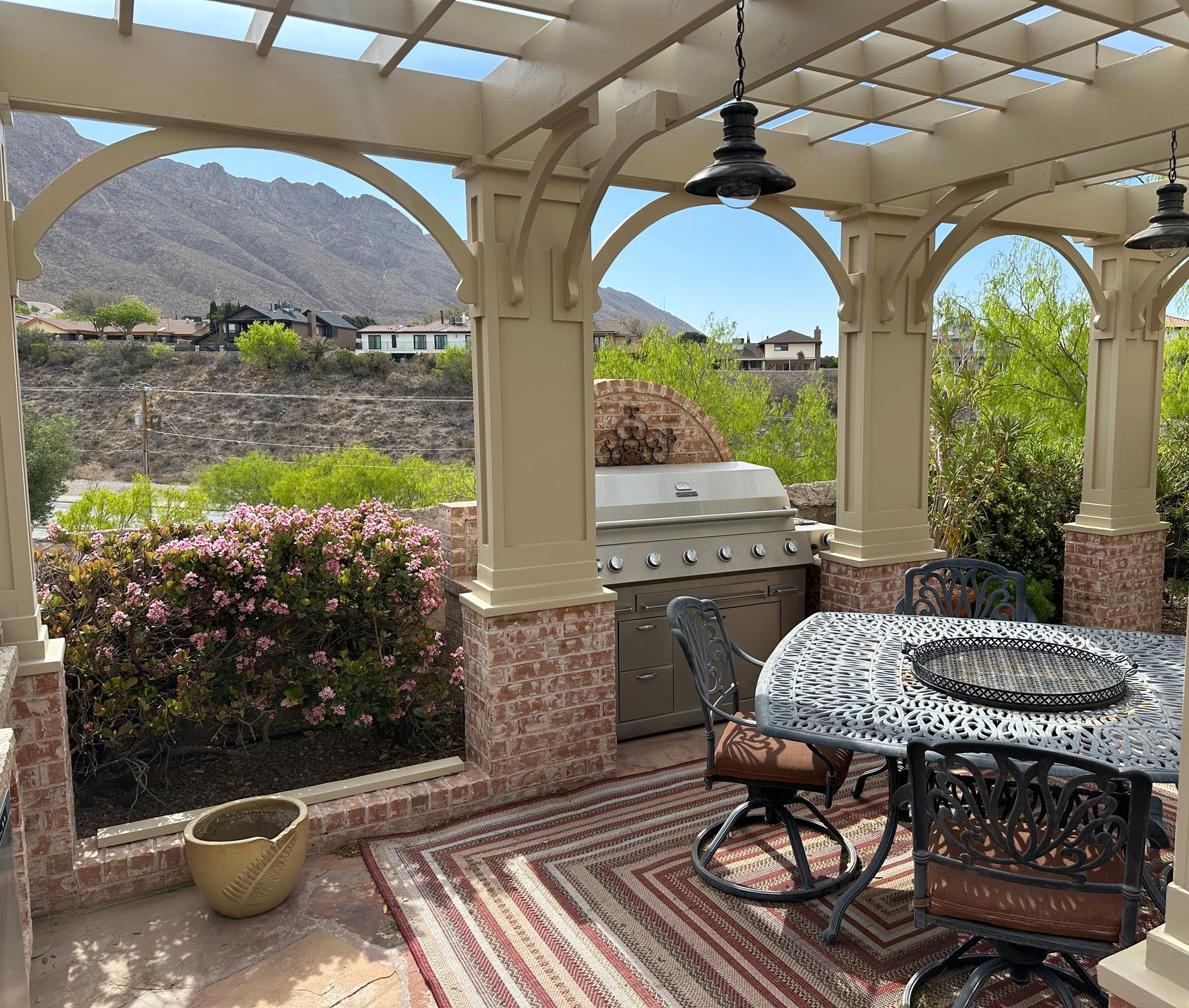 Outdoor patio with seating, stone fireplace, and hanging plants.