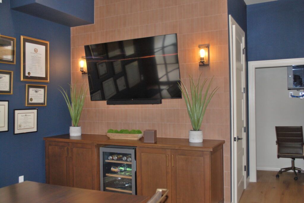 Living room with a mounted TV, wood cabinets, and decorative plants.