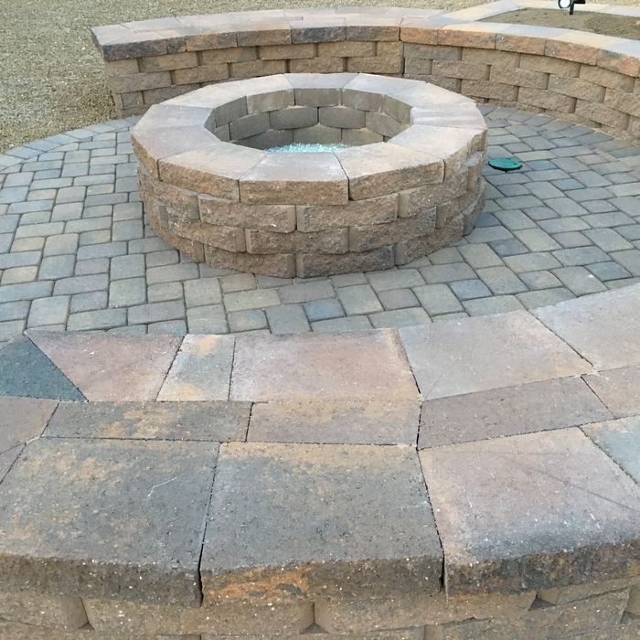 Stone fire pit with surrounding seating on a brick patio.