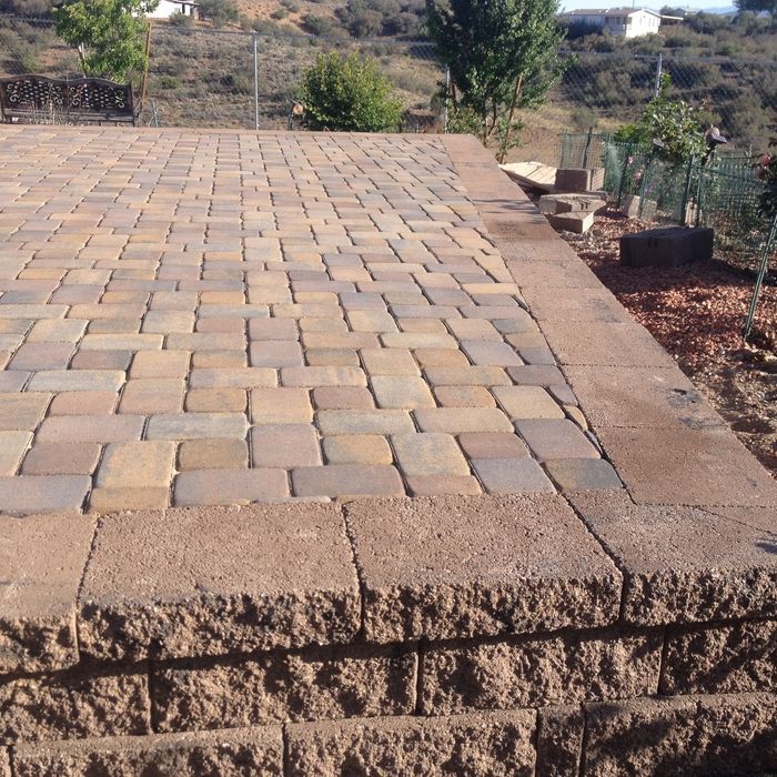 Brick patio with a retaining wall, brown and tan bricks, outdoor setting.