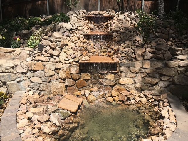 Water cascading down a layered rock waterfall into a small pond.