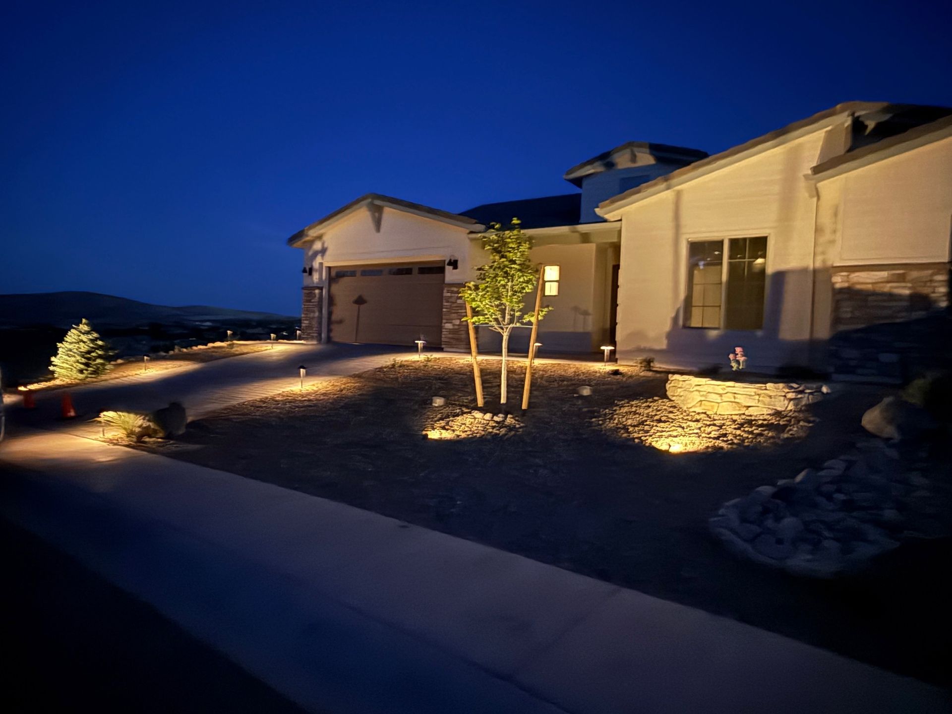 A house at night with landscape lighting illuminating the gravel and landscaping.