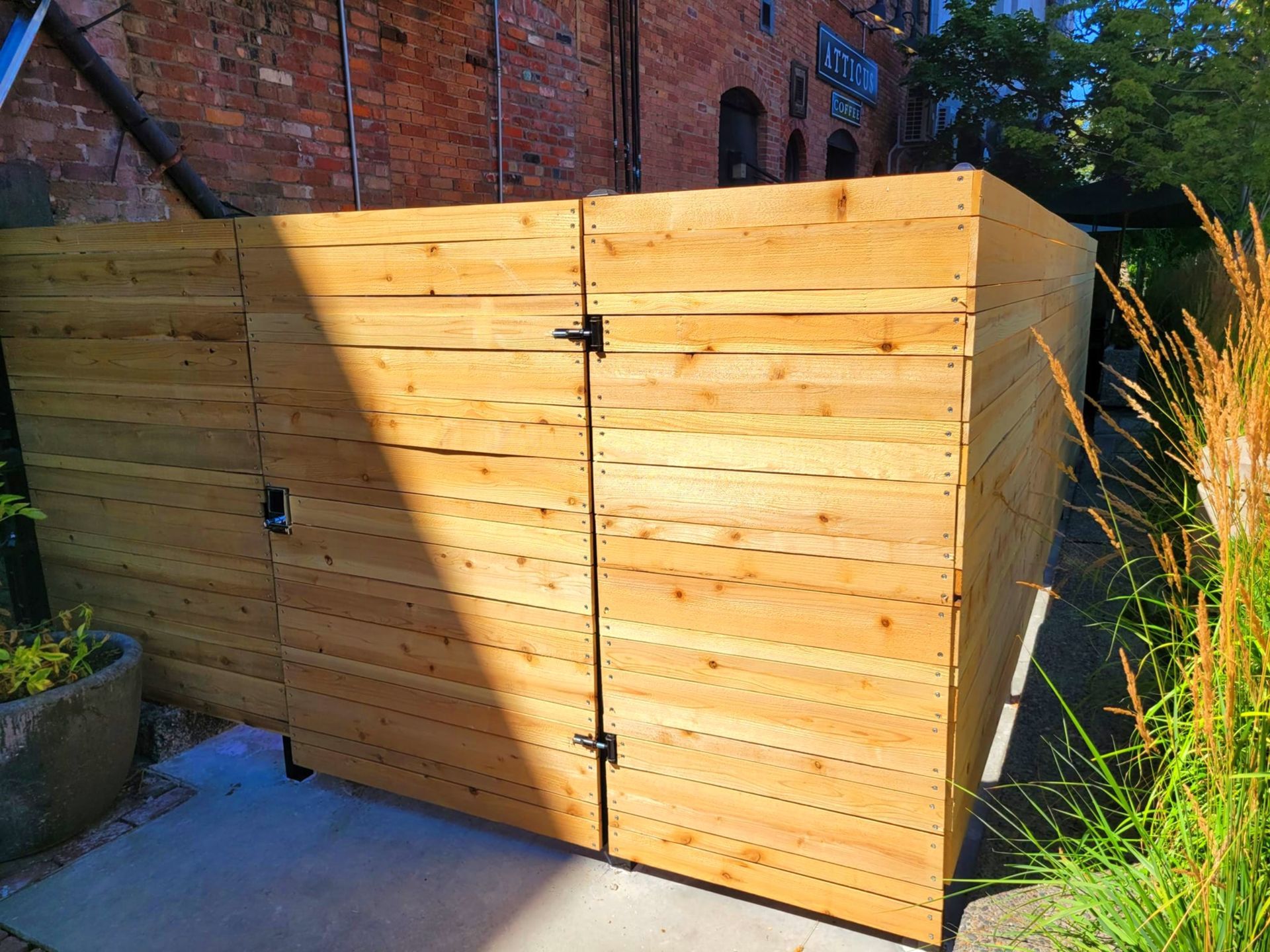 Wooden gate and fence enclose an outdoor space. Building with brick background.
