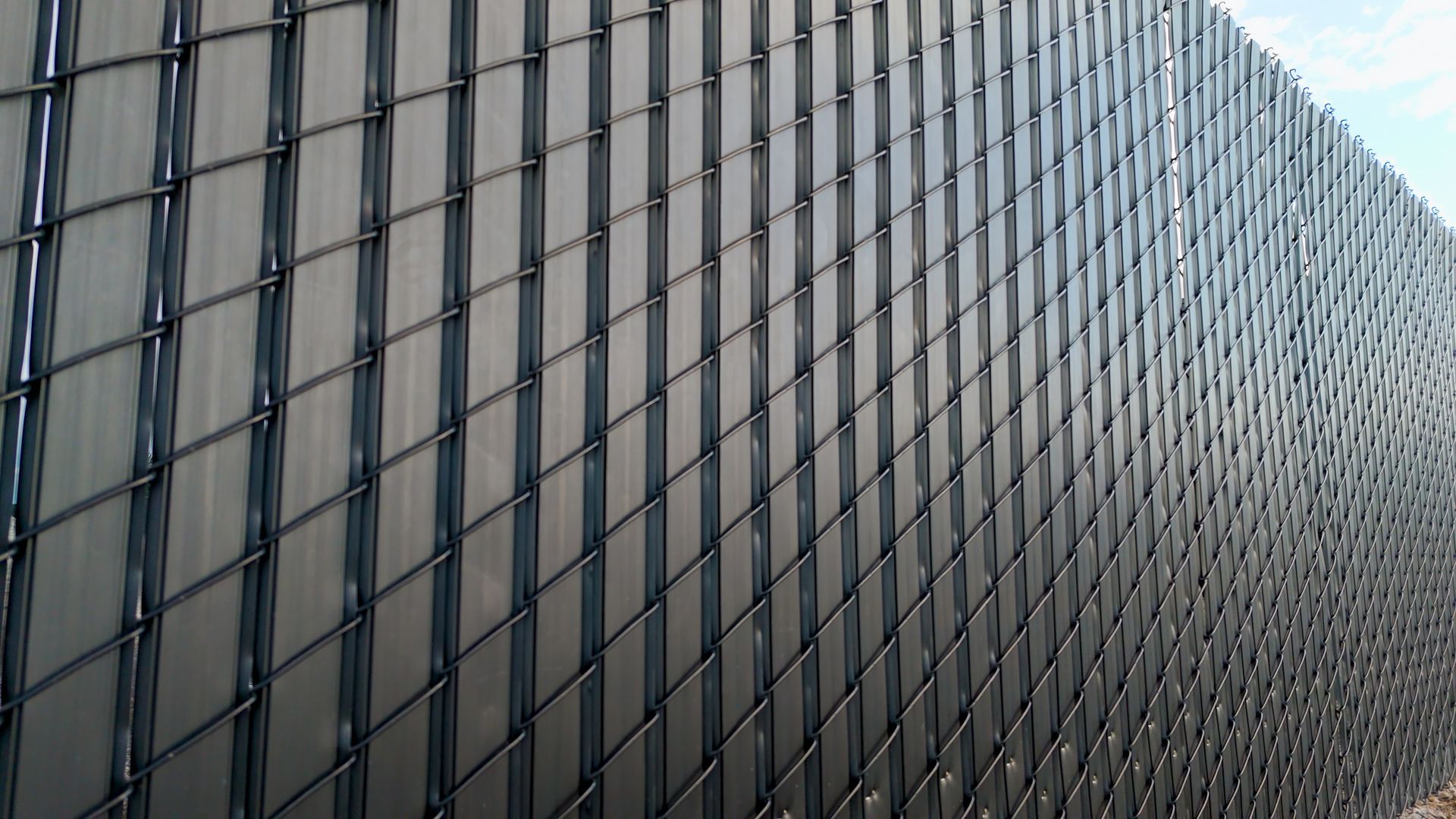 Dark gray chain-link fence with vertical privacy slats.