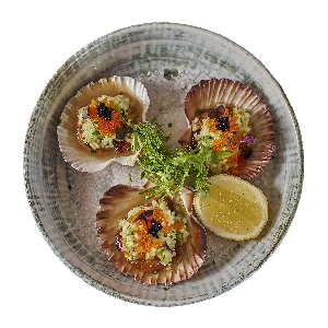 Scallops in shells on a plate, topped with garnish and caviar, served with lemon slice.