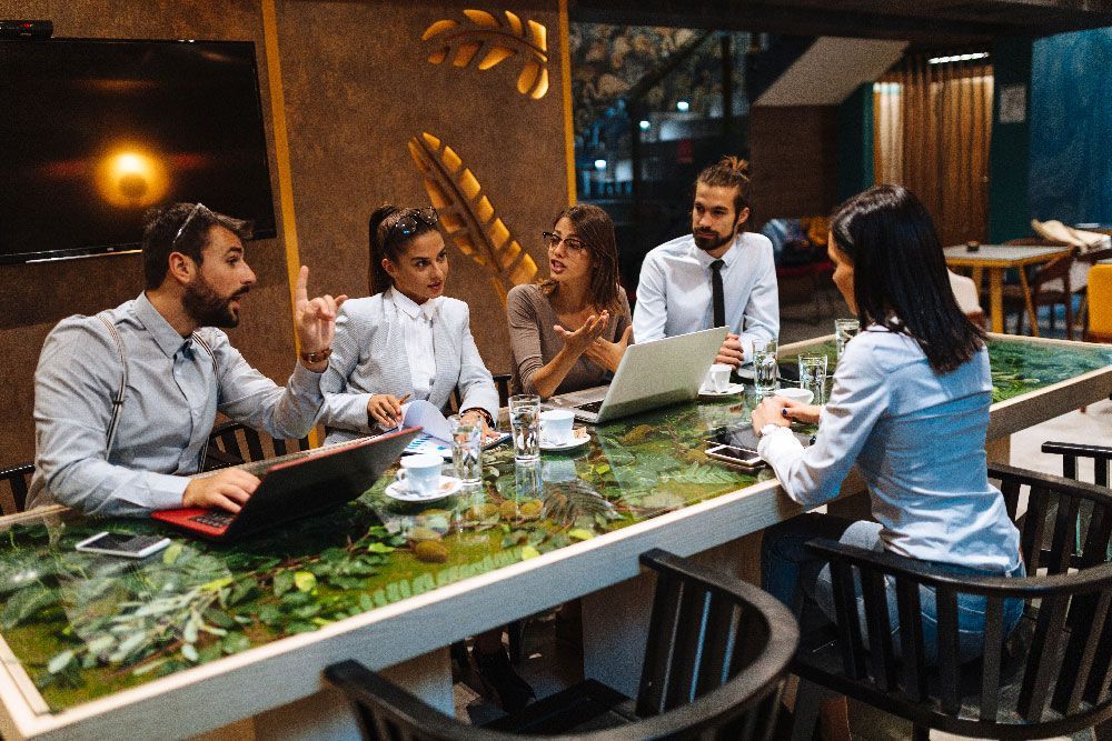 Business team in a restaurant, discussing ideas with laptops and drinks.