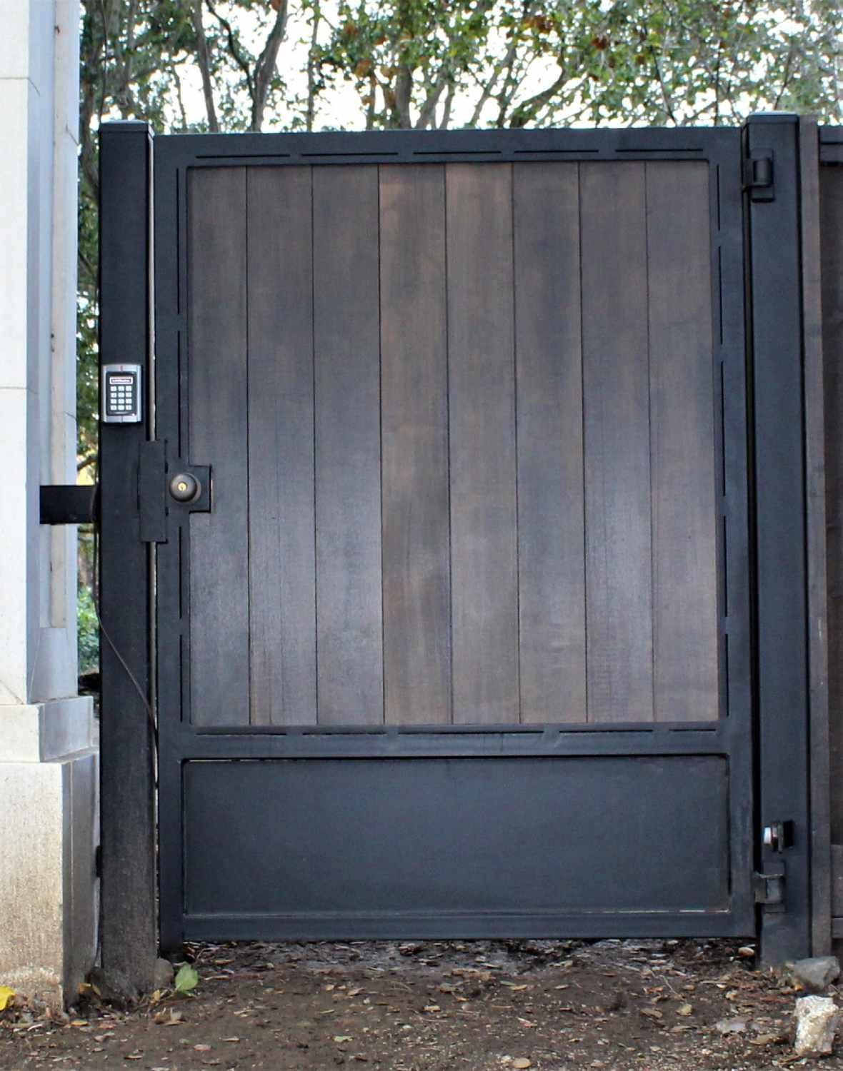 A black metal gate with a wooden panel on the side