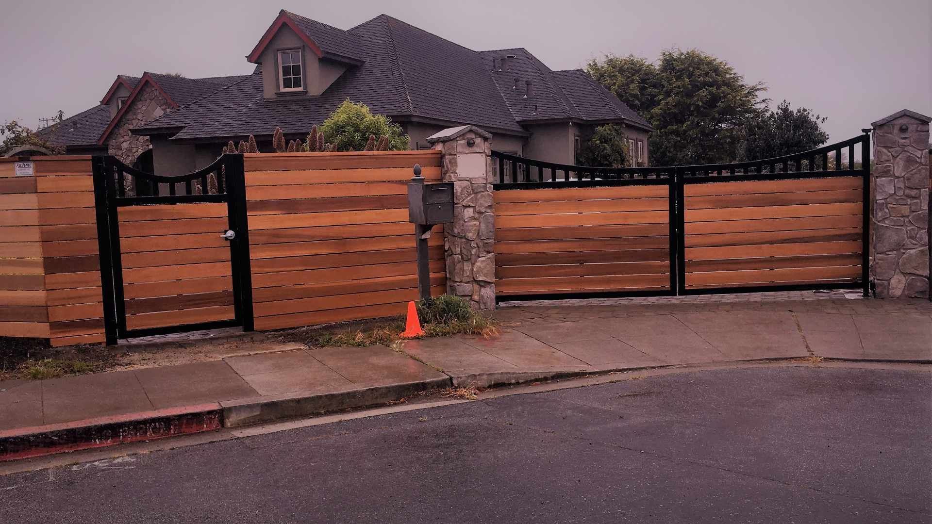 A house with a wooden fence and a gate in front of it.