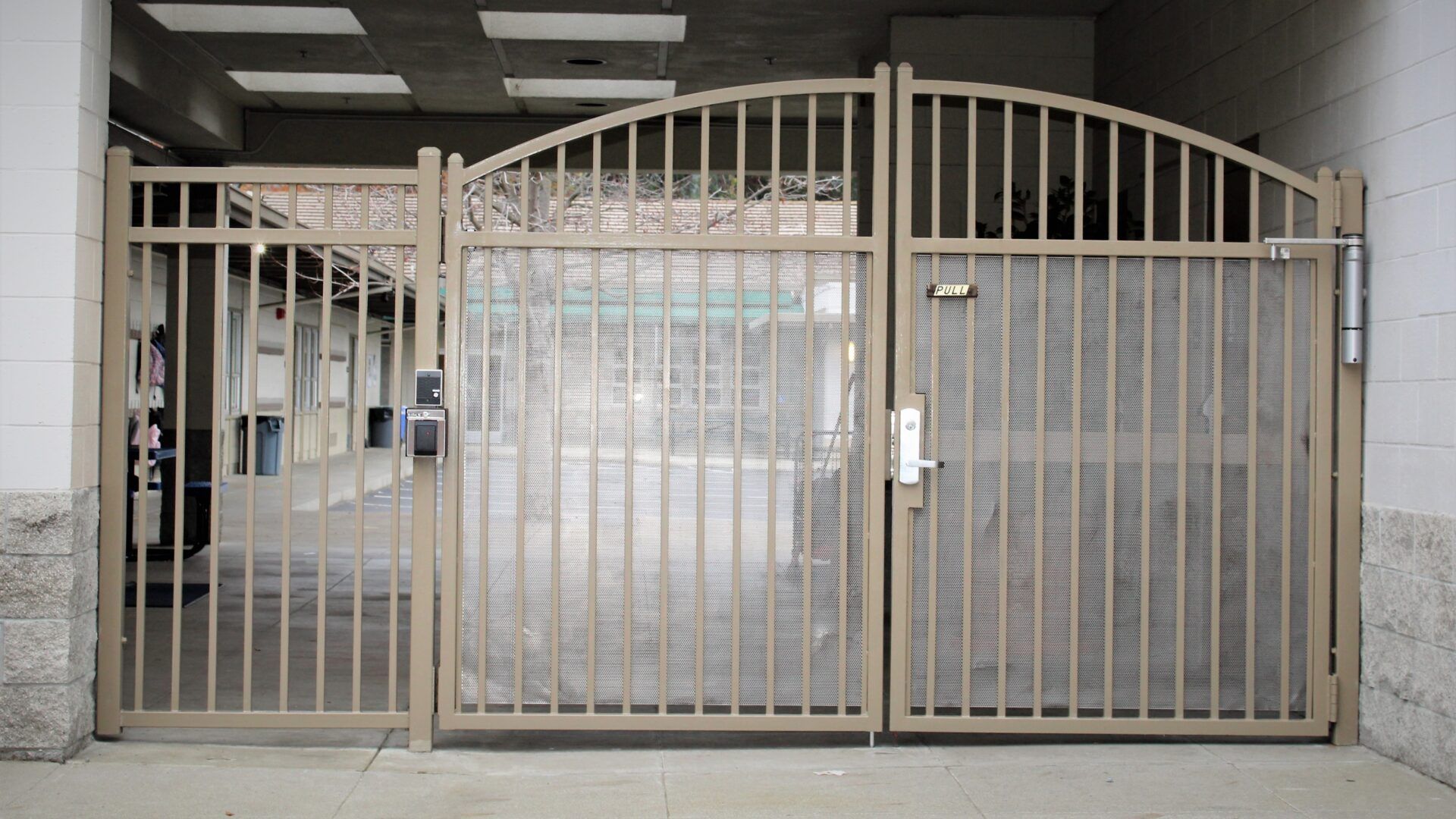 A wrought iron gate is open to a parking garage.