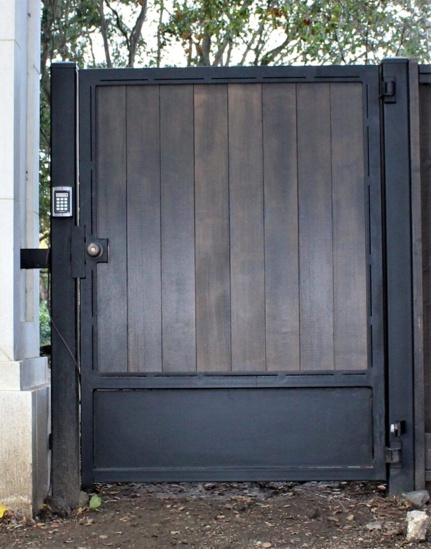 A black gate with a wooden panel on the side