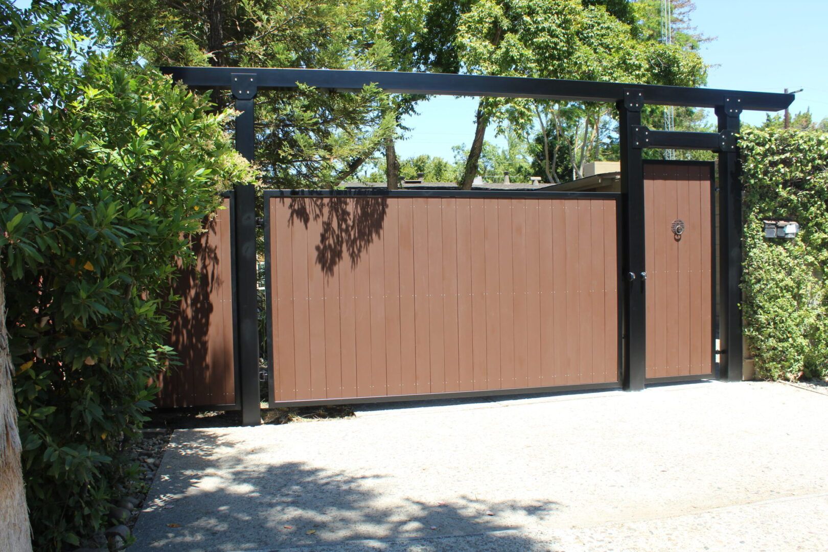 A wooden gate with a black frame is surrounded by trees