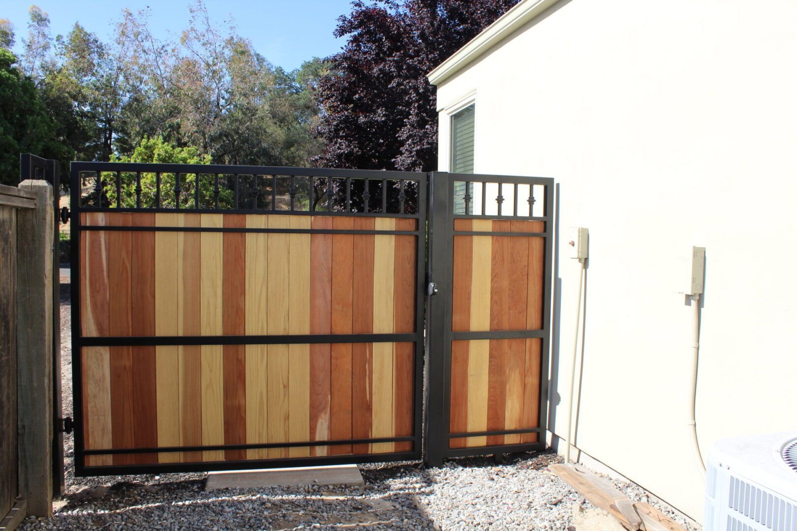 A wooden gate with a metal frame is sitting in front of a white building.