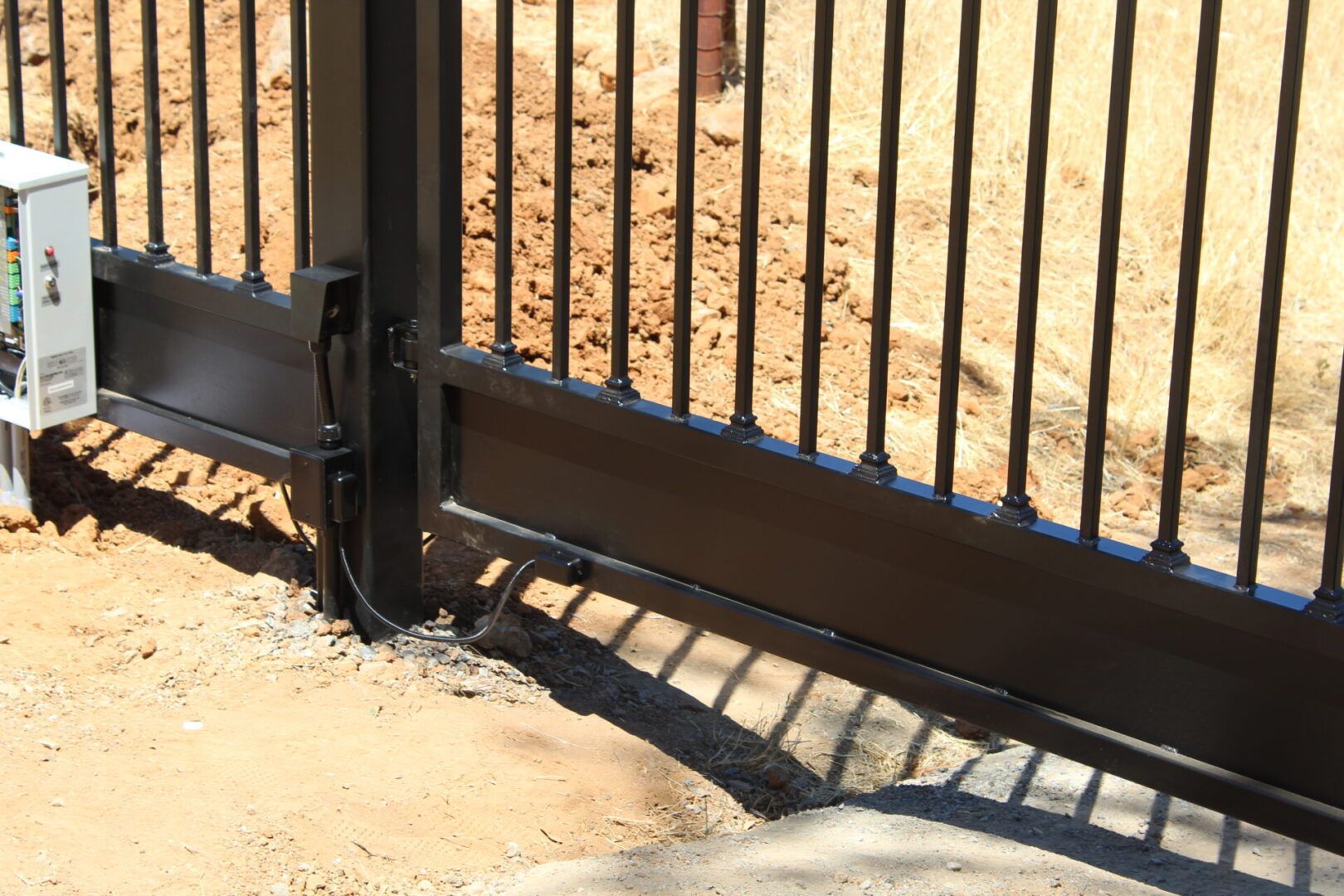 A close up of a sliding gate with a shadow on the ground.
