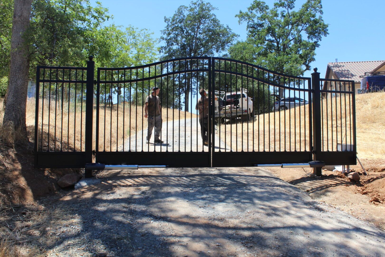 Two men are standing in front of a gate that is open