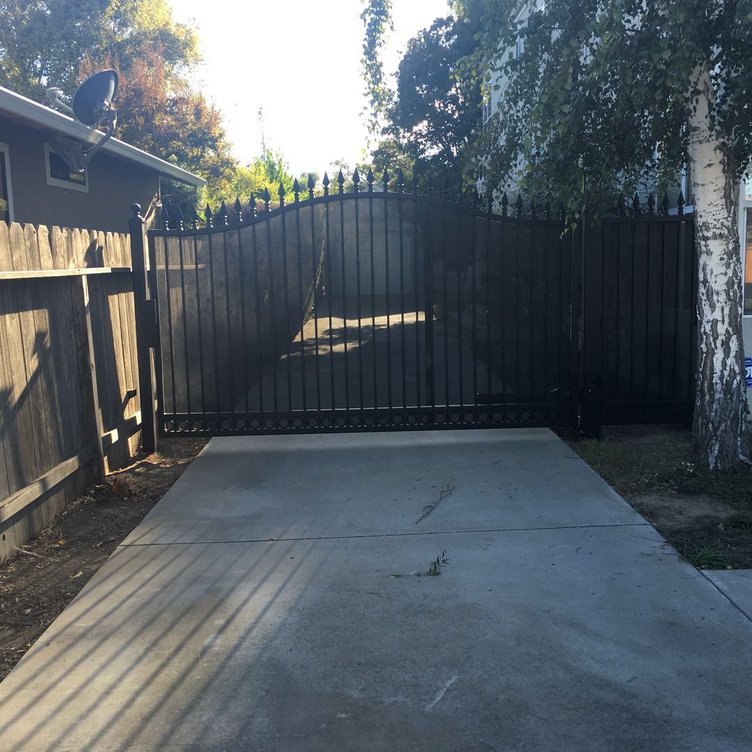 A concrete driveway leading to a metal gate