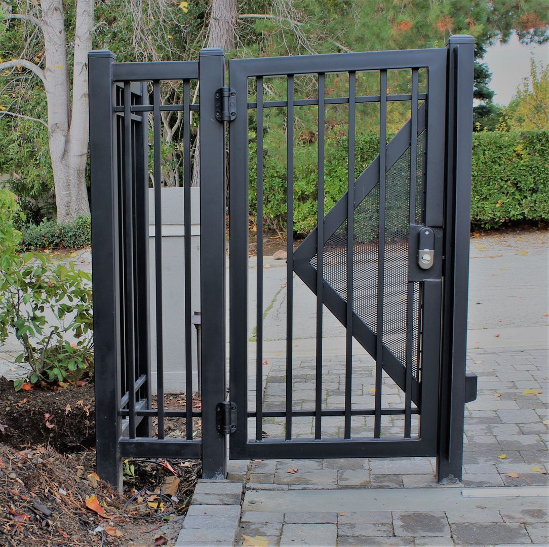 A black metal gate is open on a brick walkway.