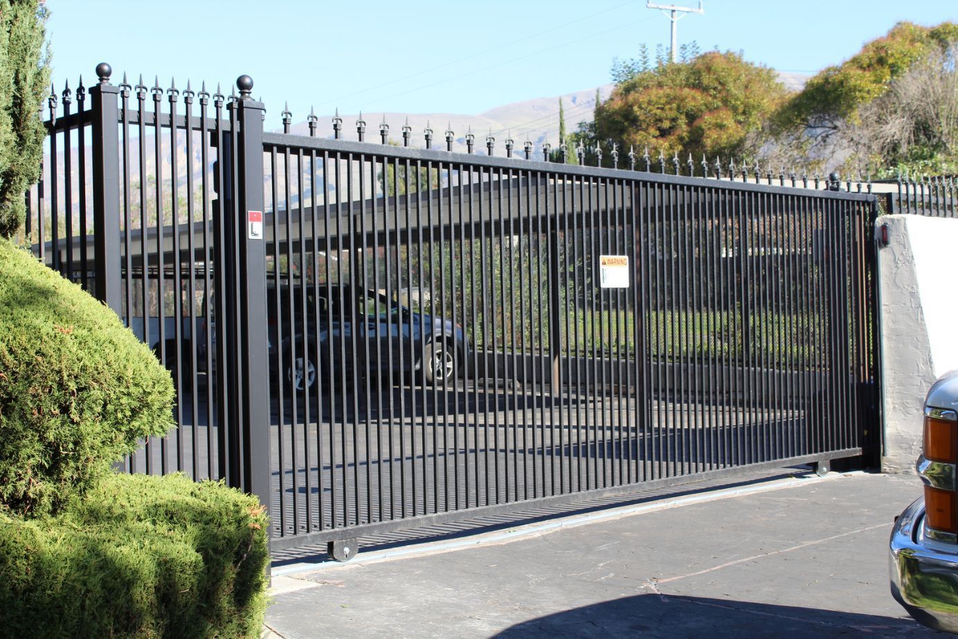 A car is parked in front of a sliding gate.