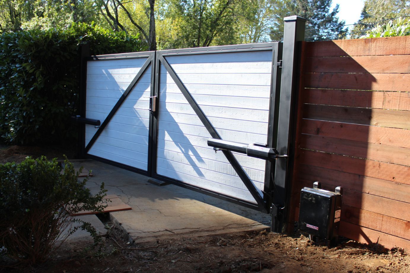 A white and black gate with a wooden fence in the background