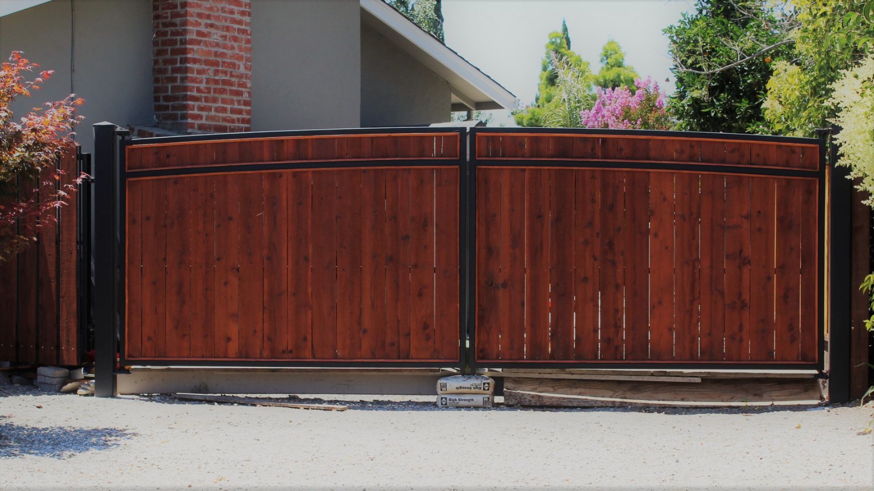 A wooden fence is in front of a brick house