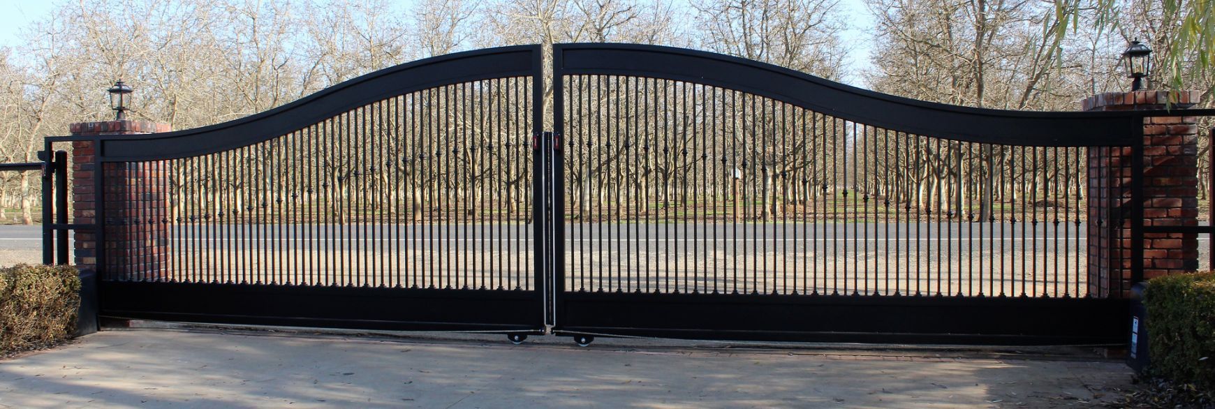 A large black gate is sitting in the middle of a driveway.
