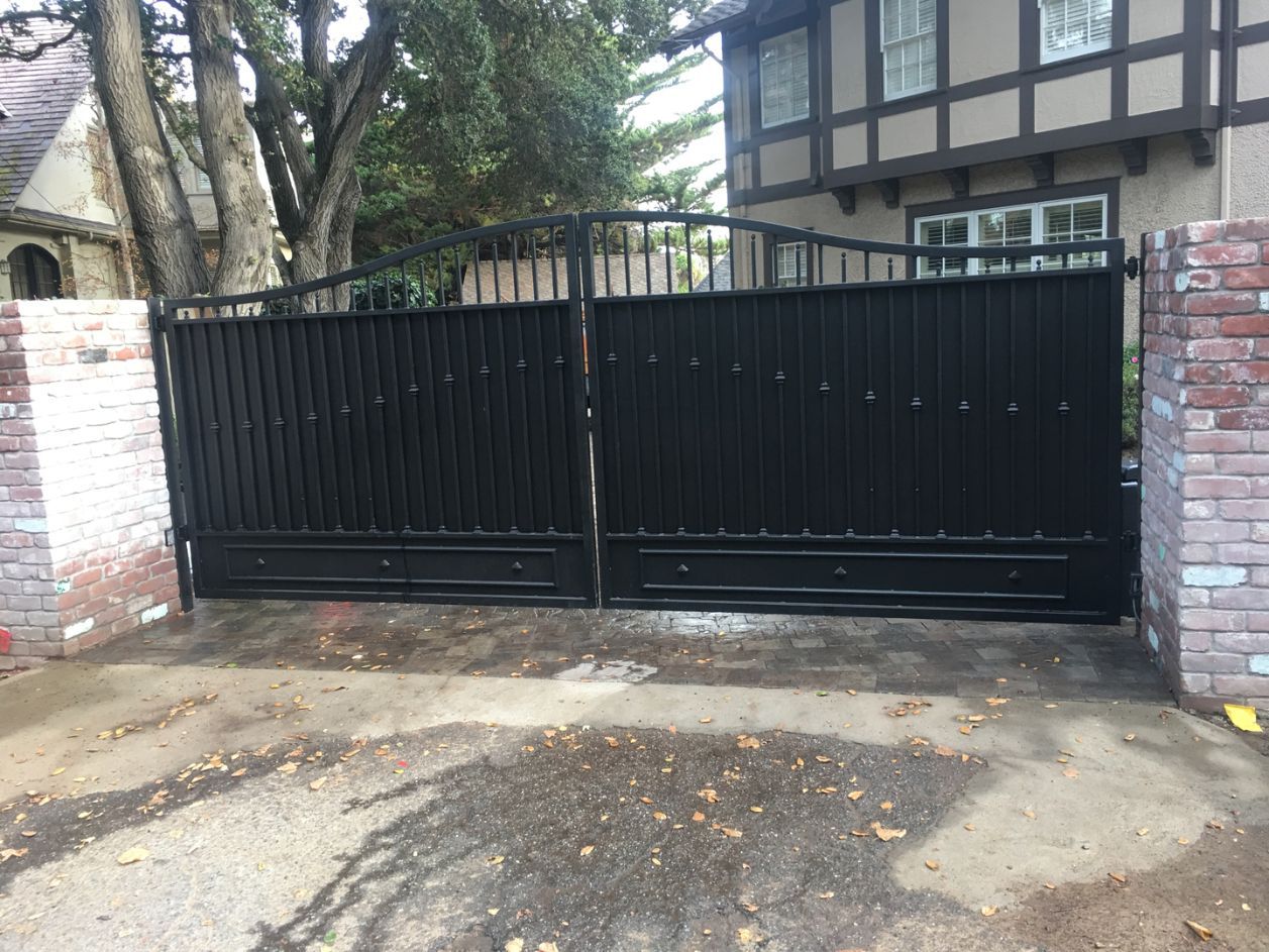 A black gate is open in front of a house.