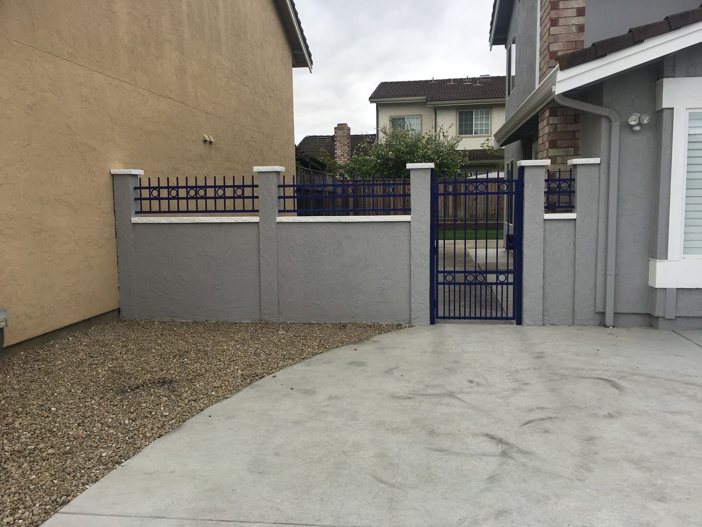 A fence with a blue gate in front of a house