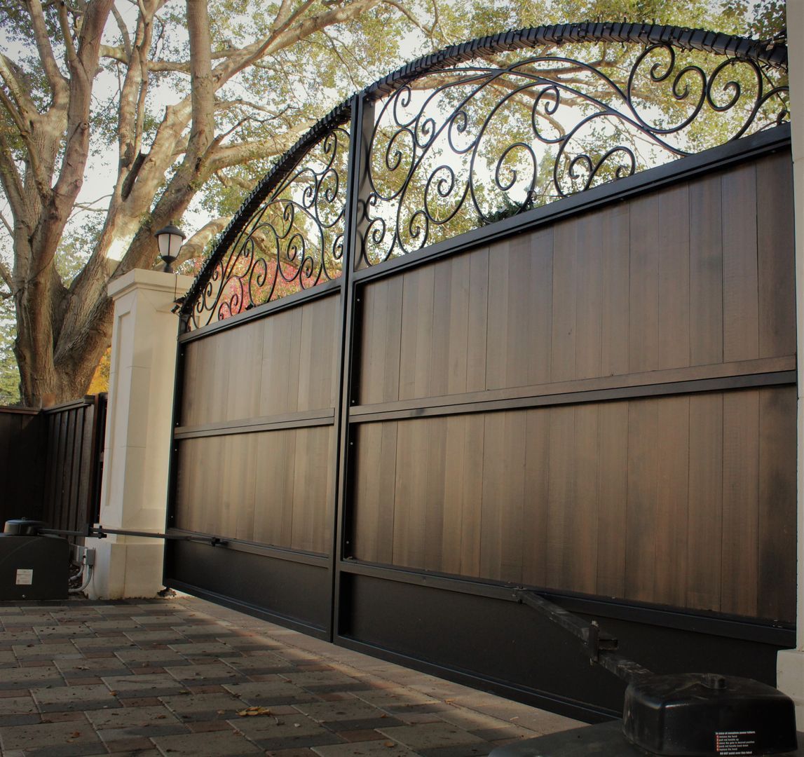 A wooden gate with a wrought iron fence around it