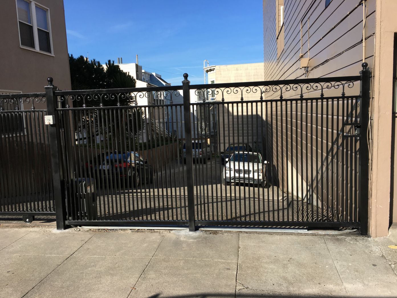 A white car is parked behind a metal gate