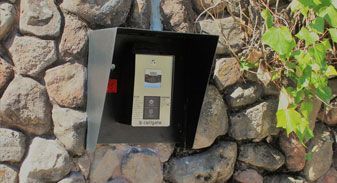 A black box is sitting on top of a stone wall.
