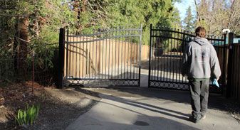 A man is walking through a gate in a driveway.