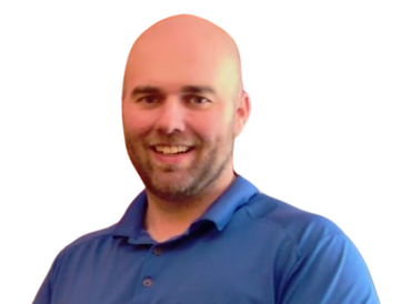 Man with a shaved head and a beard smiling, wearing a blue polo shirt.