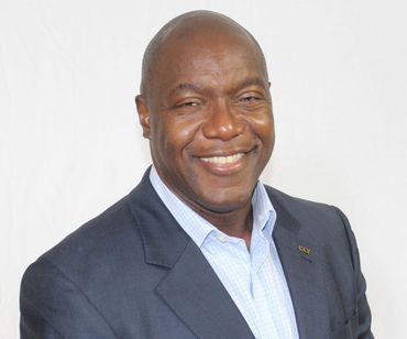 Man in blue blazer and light blue shirt, smiling.