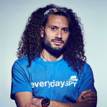 Man with curly hair and a headband wearing a blue 
