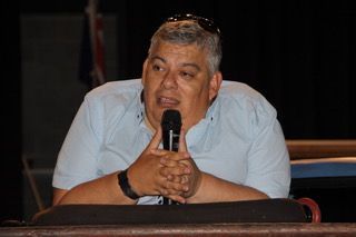 Woman with light skin, blue eyes, smiling, wearing a blue top, against a pale background.