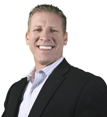 Man in a black suit smiling, wearing a light blue and white striped shirt.