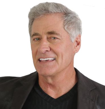 Man with gray hair, smiling, wearing a dark jacket. White background.