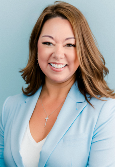 Woman with brown hair smiles, wearing a light blue blazer, against a blue background.
